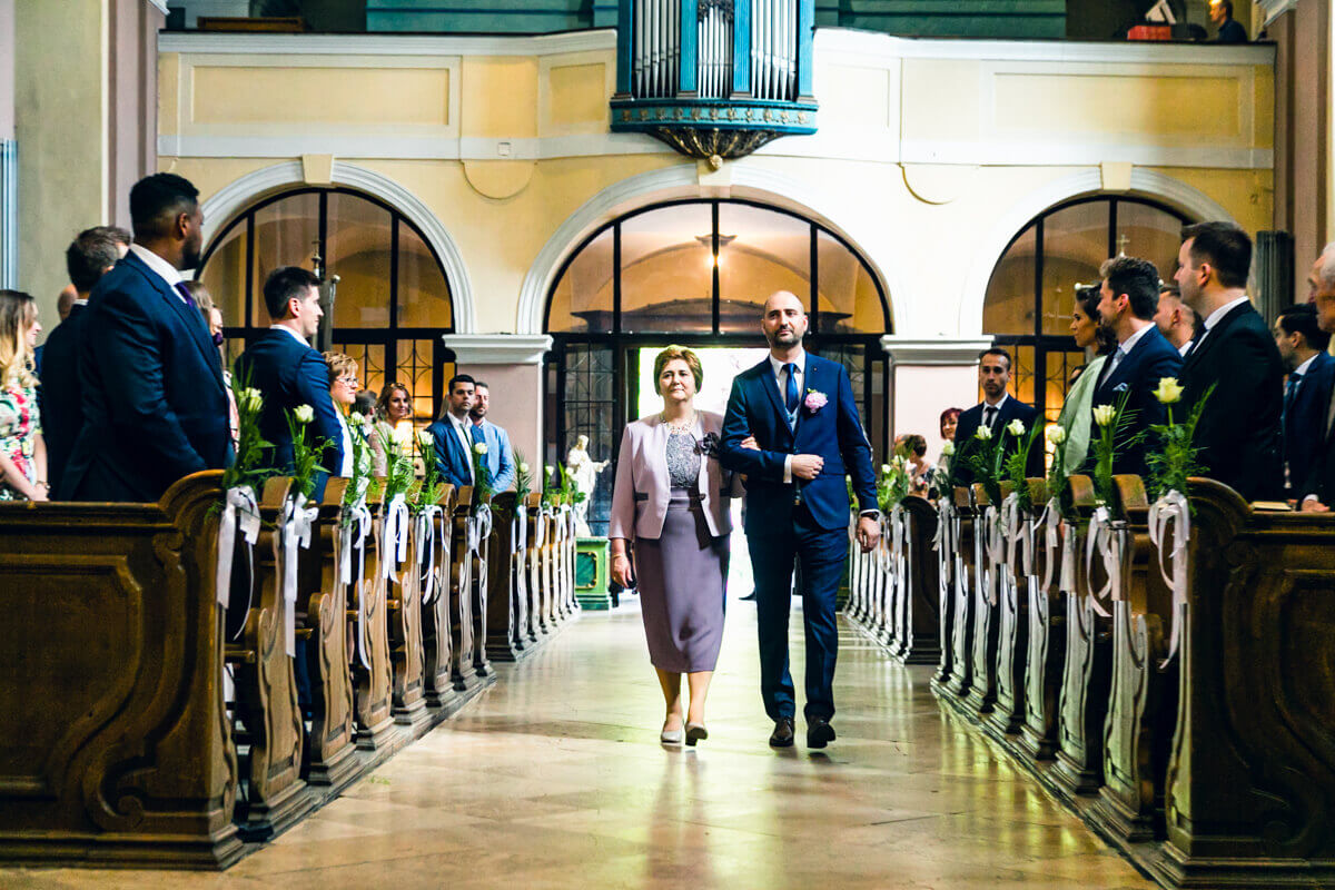 Esküvő fotózás során készült fotó Gergőről, aki besétál a templomba az anyukájával.