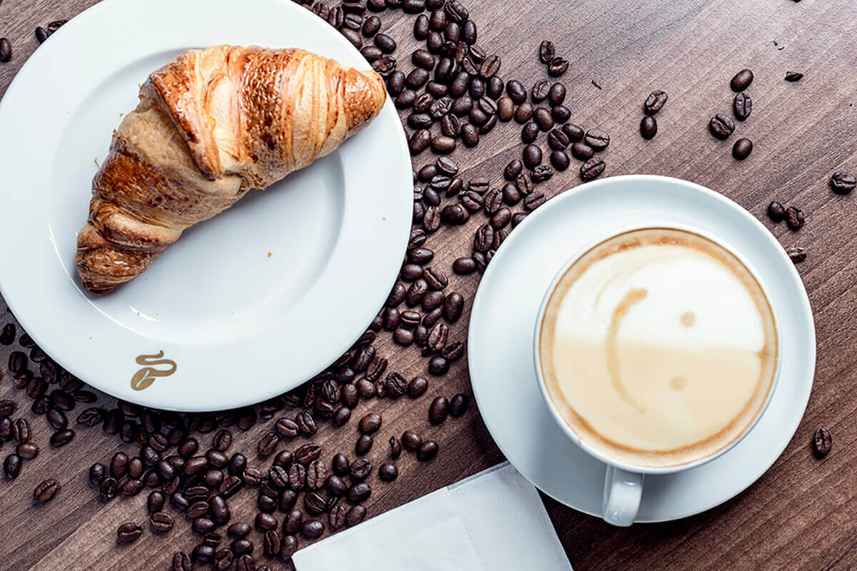 Reklámfotózás során készített termékfotó egy kávéról és egy croissantról.